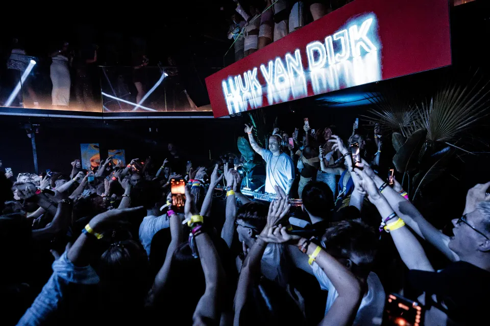Novamondo crowd with hands raised beneath the stage screen at AURA